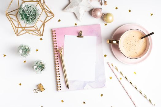 Desktop blank planner. Flat lay of white working table background with cup of coffee and Christmas decoration. Top view balls, fir tree, paper clips, mock up greeting card, craft Notebook and pen.