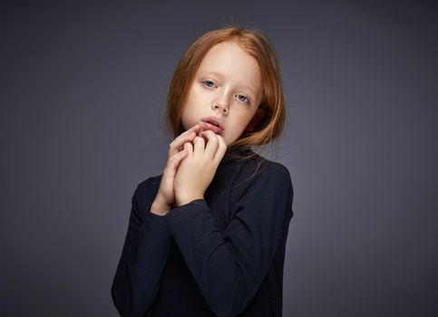 red-haired girl with freckles on her face in a black sweater posing. High quality photo