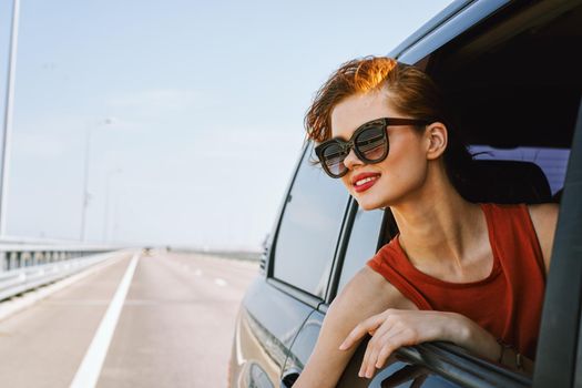 a woman is driving in a car on the road and looking out of the window. High quality photo