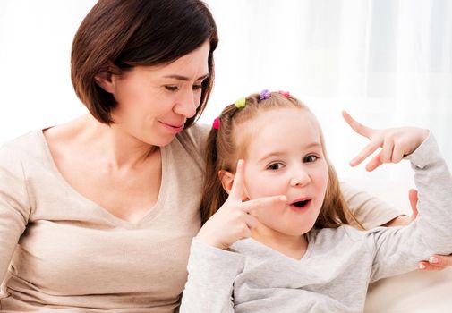 Mother and little daughter smiling, Pretty girl making her mother smile. Daughter and mom having fun together