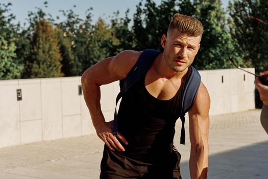 athletic man in black t-shirt with dumbbells in the park training. High quality photo