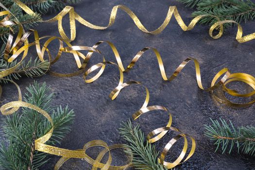 Christmas composition of fir branches and a gold ribbon on a black oil with gold embossing background