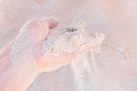 The guy's hand takes or touches the white beach sand close up.