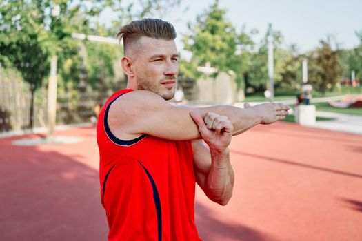 sports man in a red t-shirt on the sports ground doing exercises. High quality photo
