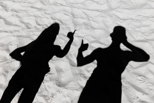 Black shadow silhouette of men and women gesticulating hands on white beach sand background.