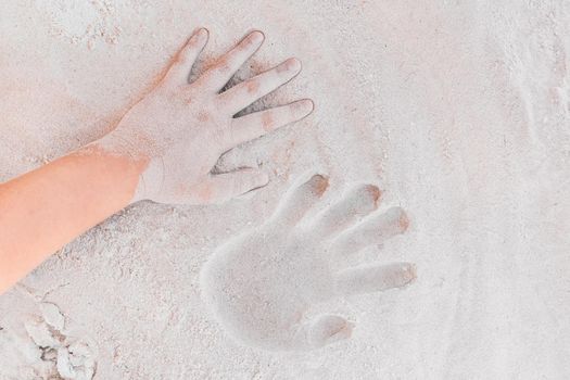 Trace or handprint of a young girl close up on the white beach sand background.