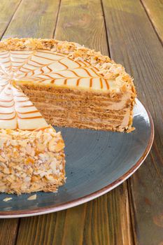 Cut caramel cake on plate on wooden table close up