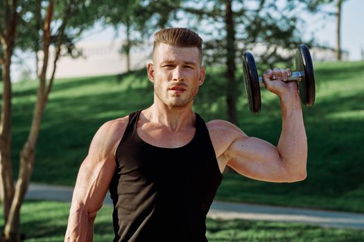 pumped up sports Vykhino in the park with dumbbell workout. High quality photo