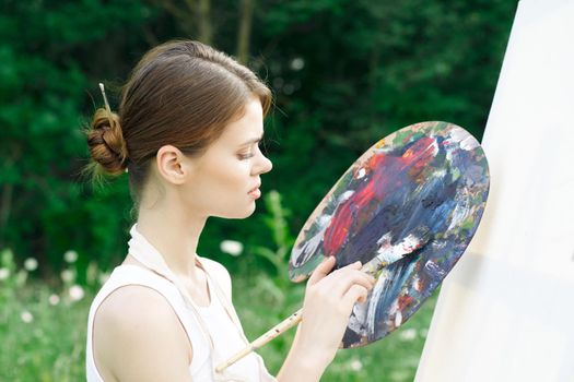 woman artist paints palette easel nature drawing. High quality photo