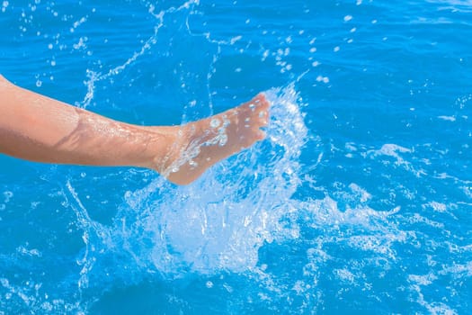 A young girl's leg sprays blue light sea water close-up. Soft focus.