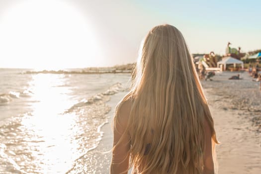 Long hair of a young girl against the sea beach and sunset background.