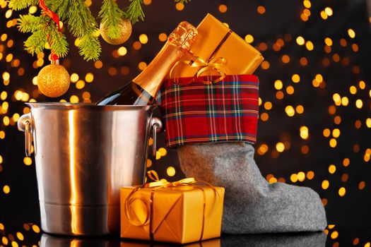 Champagne bottle and Christmas stocking with gifts against garland