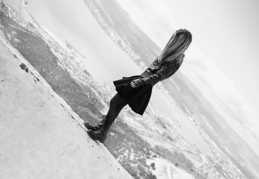 Fashionable beautiful young woman standing on edge over the sea bay outdoor. Black and white image