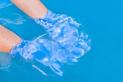 The hands of a young girl under a blue clean cold sea water close-up.