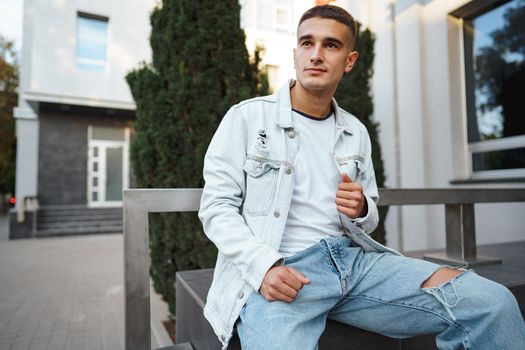 Young casual man sitting on stairs alone on city street