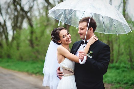 bride and groom on a rainy wedding day walking under an umbrella