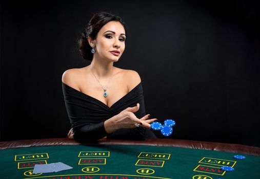 sexy woman with poker cards and chips. Female player in a beautiful black dress. girl sitting at the poker table and bets