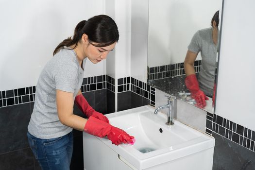 woman cleaning bathroom sink with a brush