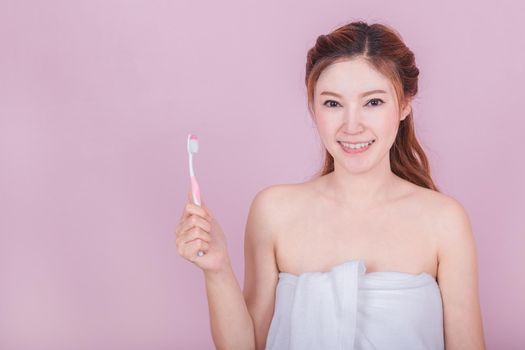 happy beautiful woman brushing her teeth on pink background