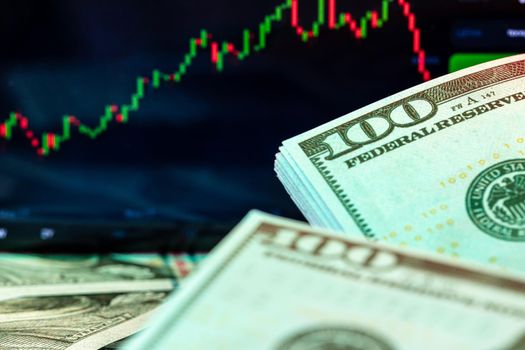 Dollars in front of a monitor with a price chart. Forex and trading. Close up.