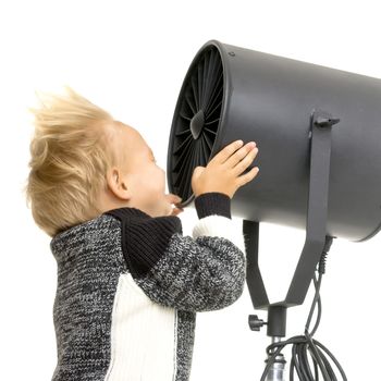 Fan in a photo studio. Boy relaxing in front of a fan at home. Summer heat