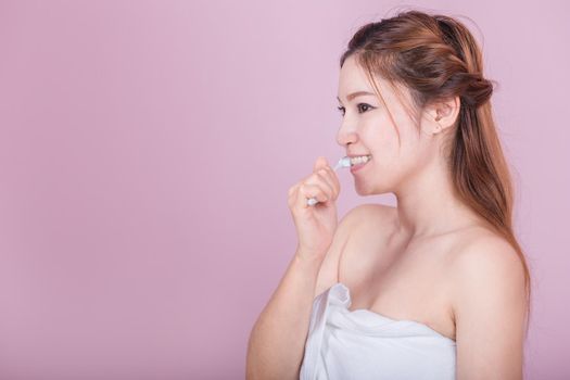 happy beautiful woman brushing her teeth on pink background