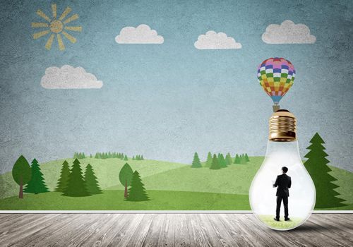 Businessman inside light bulb in room against nature drawn concept