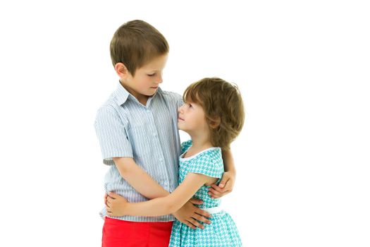 Charming little girl hugging a tall boy with blond hair. A romantic couple is happy with the joint time brought. A happy sister hugs her brother. The concept is a happy childhood. Isolated on white background.