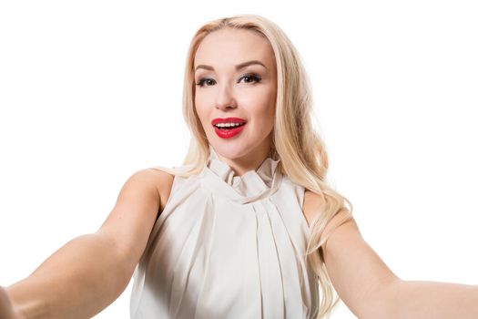 Smiling cheerful blond-haired woman doing selfie on isolated white background. Taking picture.