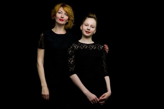 Happy family mom and little daughter, studio portrait.On black background