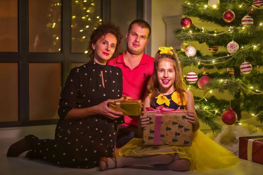 Happy young family with children at Christmas near a Christmas tree and a fireplace. The concept of holidays, winter, Christmas, Happy childhood, the harmonious development of children in the family.
