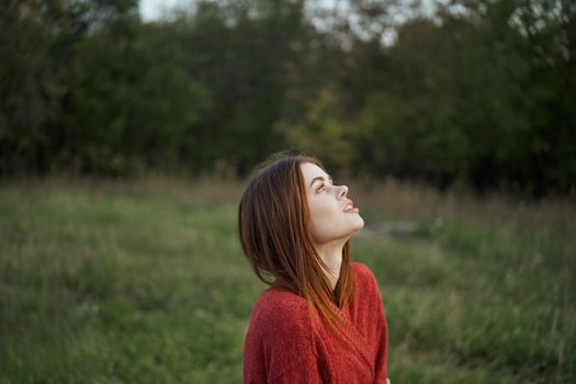 woman in a red sweater outdoors in the field nature rest. High quality photo