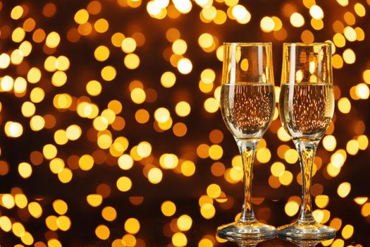 Two glasses of Champagne against shiny bokeh lights background