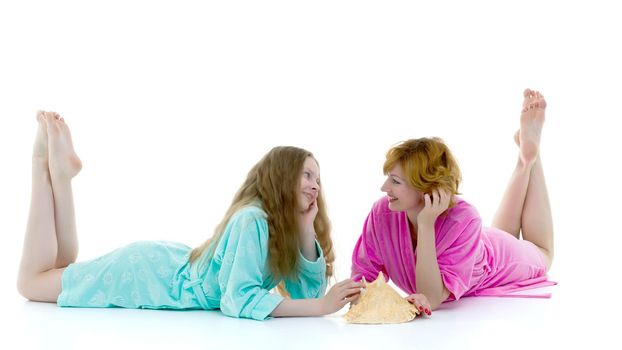 Daughter and mother in bath robes in a photo studio. The concept of relaxation, cosmetics. Isolated on white background