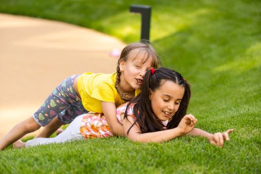 Portrait of two little girls sisters fighting on home backyard. Friends girls having fun. Lifestyle candid family moment of siblings quarreling playing together.