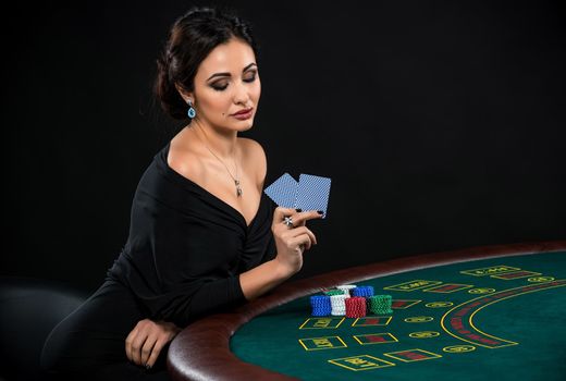 sexy woman with poker cards and chips. Female player in a beautiful black dress