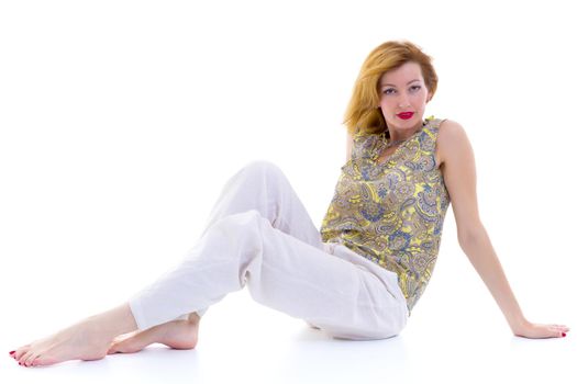 Beautiful young woman sitting on the floor of a studio. The concept of style and fashion. Isolated on white background.