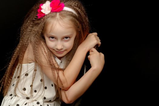 Beautiful little girl, studio portrait on a black background. The concept of a happy childhood, style and fashion.