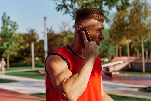 athletic man talking on the phone in the park. High quality photo