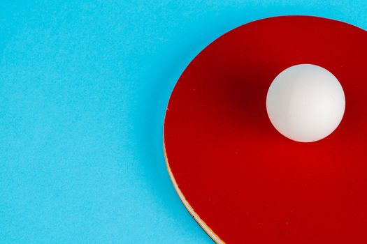 Red ping pong racket on a blue background. Close up.