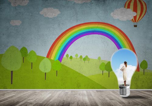 Businesswoman inside light bulb in room against nature drawn concept