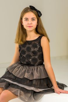 Beautiful Girl Sitting on Ledge of the Wall and Smiling at Camera, Portrait of Pretty Blonde Teenage Girl in Stylish Clothing Posing in Studio