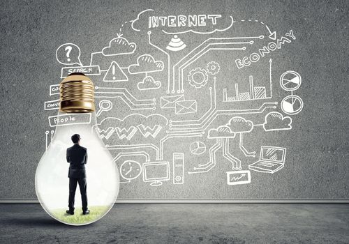 Businessman inside of light bulb in empty concrete room and sketches on wall