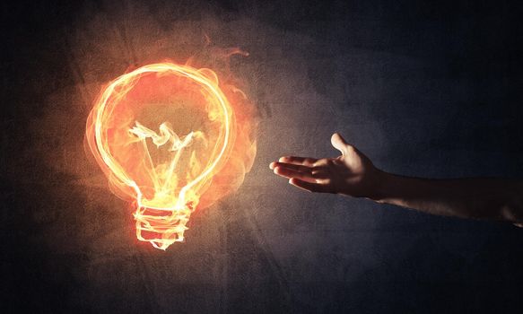 Close of man hand showing at glowing fire light bulb icon