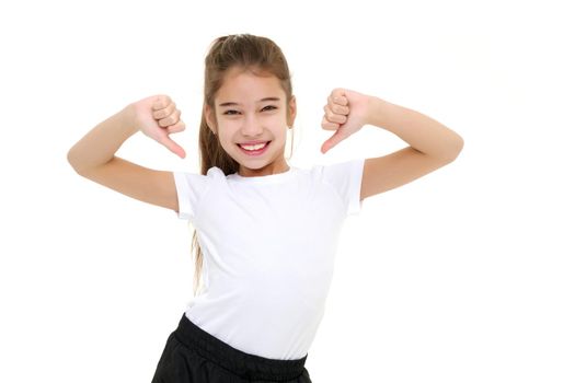 A beautiful little girl in an empty white T-shirt points to herself. The concept of design of T-shirts, advertising of children's goods. Isolated on white background.