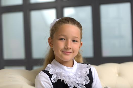 Cute little girl in school uniform near a large panoramic window.