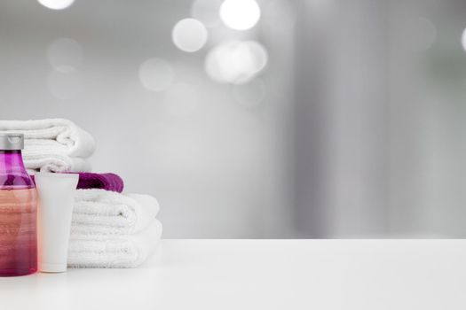 Spa still life with towels and skincare cosmetics against blurred background, close up