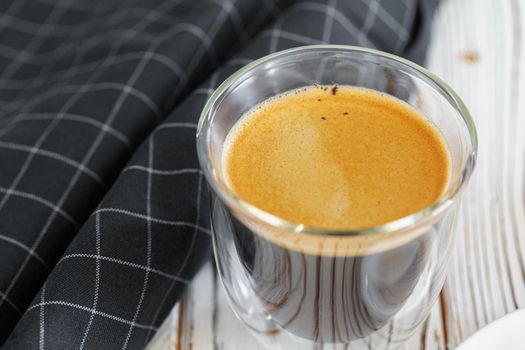 Glass cup of coffee on white wooden kitchen table