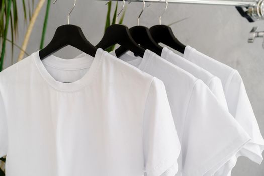 Row of white t-shirts on hangers hanging on rack
