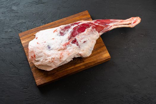 Fresh raw lamb leg ready for roasting on wooden board, top view.